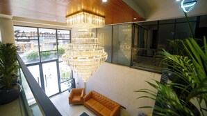 A modern lobby with a large chandelier, leather sofas, and potted plants. - Hotel shri anand Vilas (Bhopal)