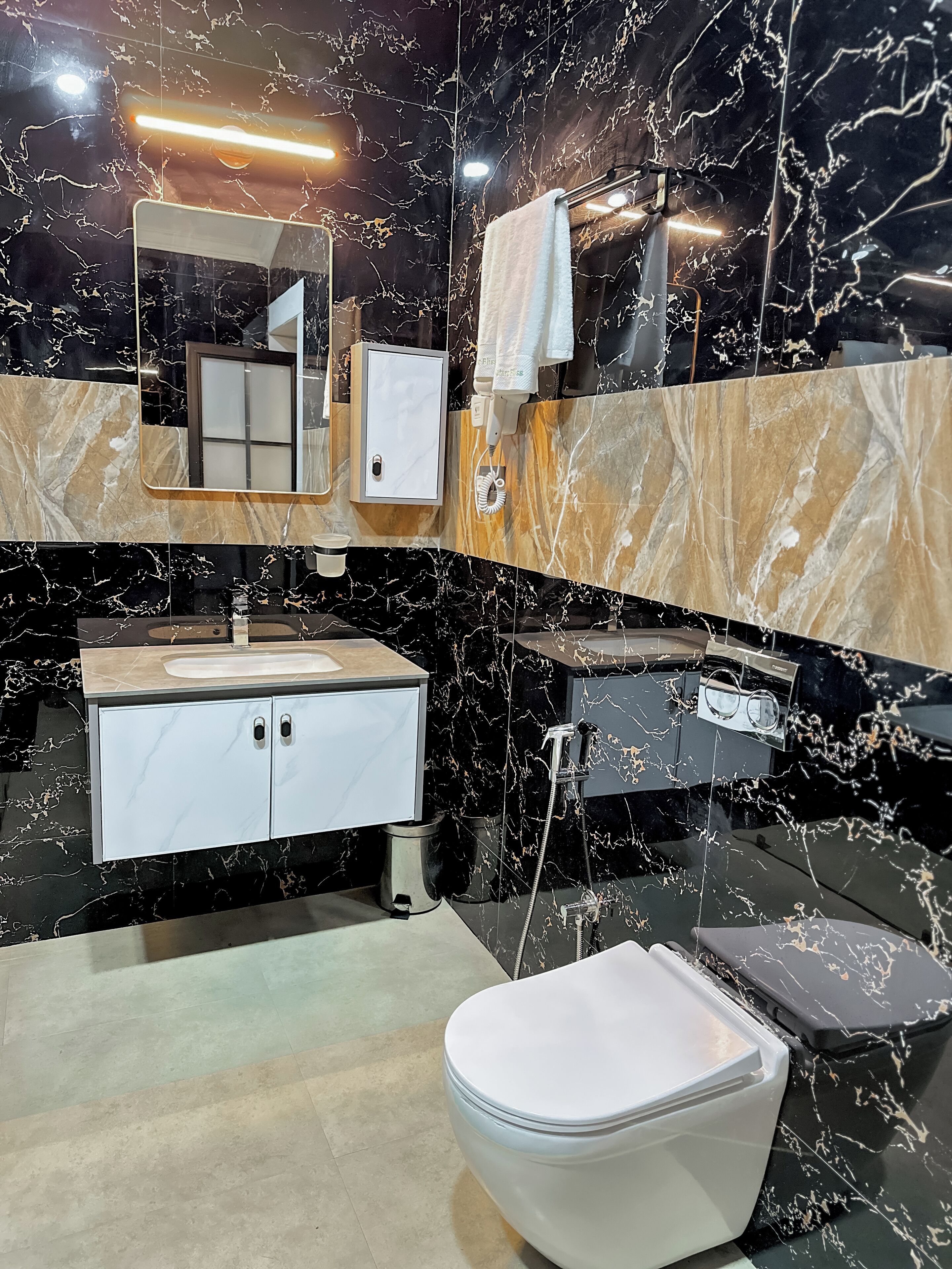 A modern bathroom with a marble vanity, a toilet, and a shower area.
