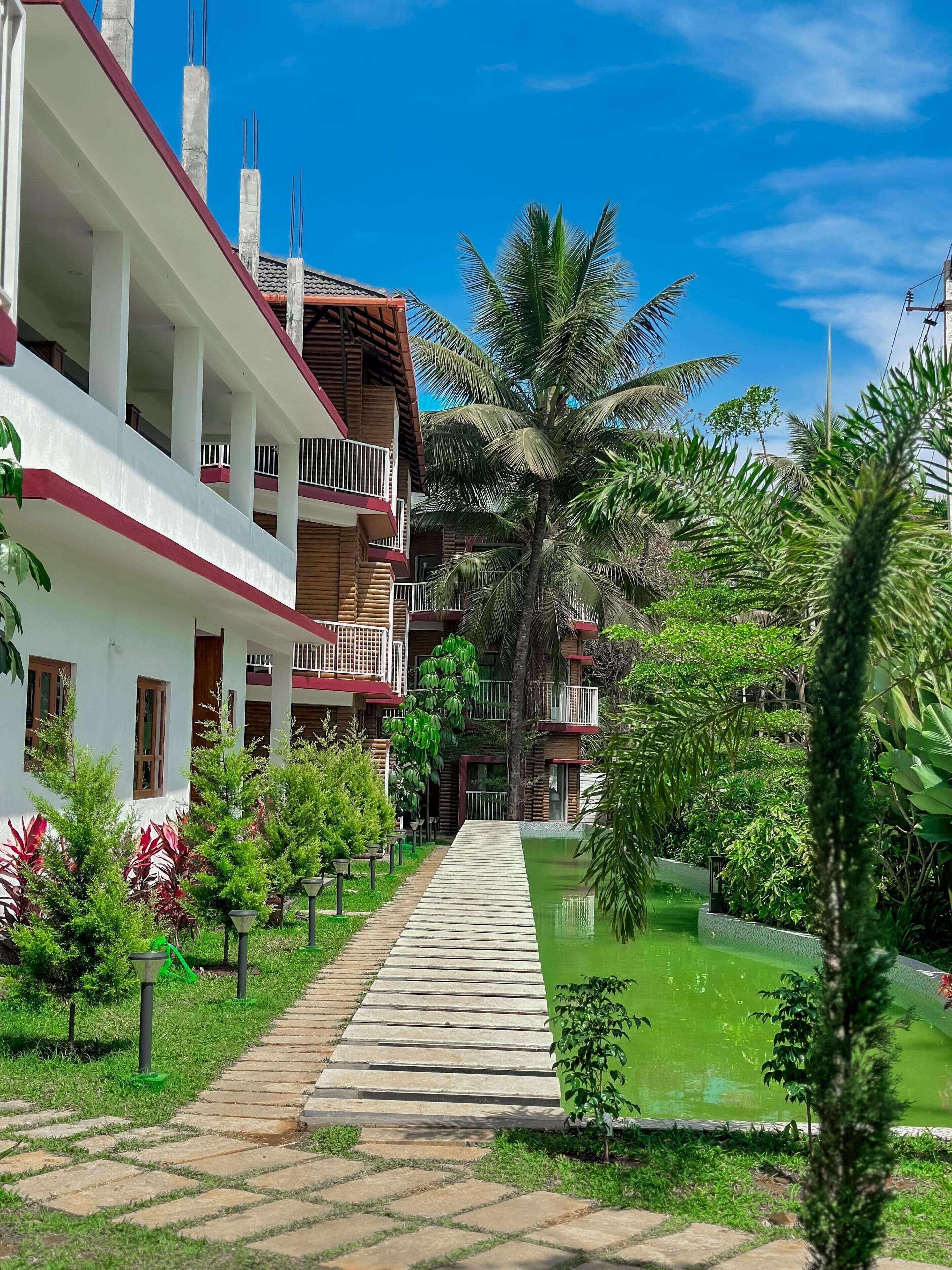 A hotel with multiple floors, outdoor pools, and lush greenery.