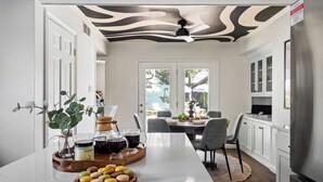 A modern kitchen with a marble countertop, a ceiling fan, and a dining area with a table and chairs.