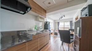 A modern kitchen with wooden cabinets, a stainless steel countertop, and a built-in oven. - SPACE 701 (Sapporo)