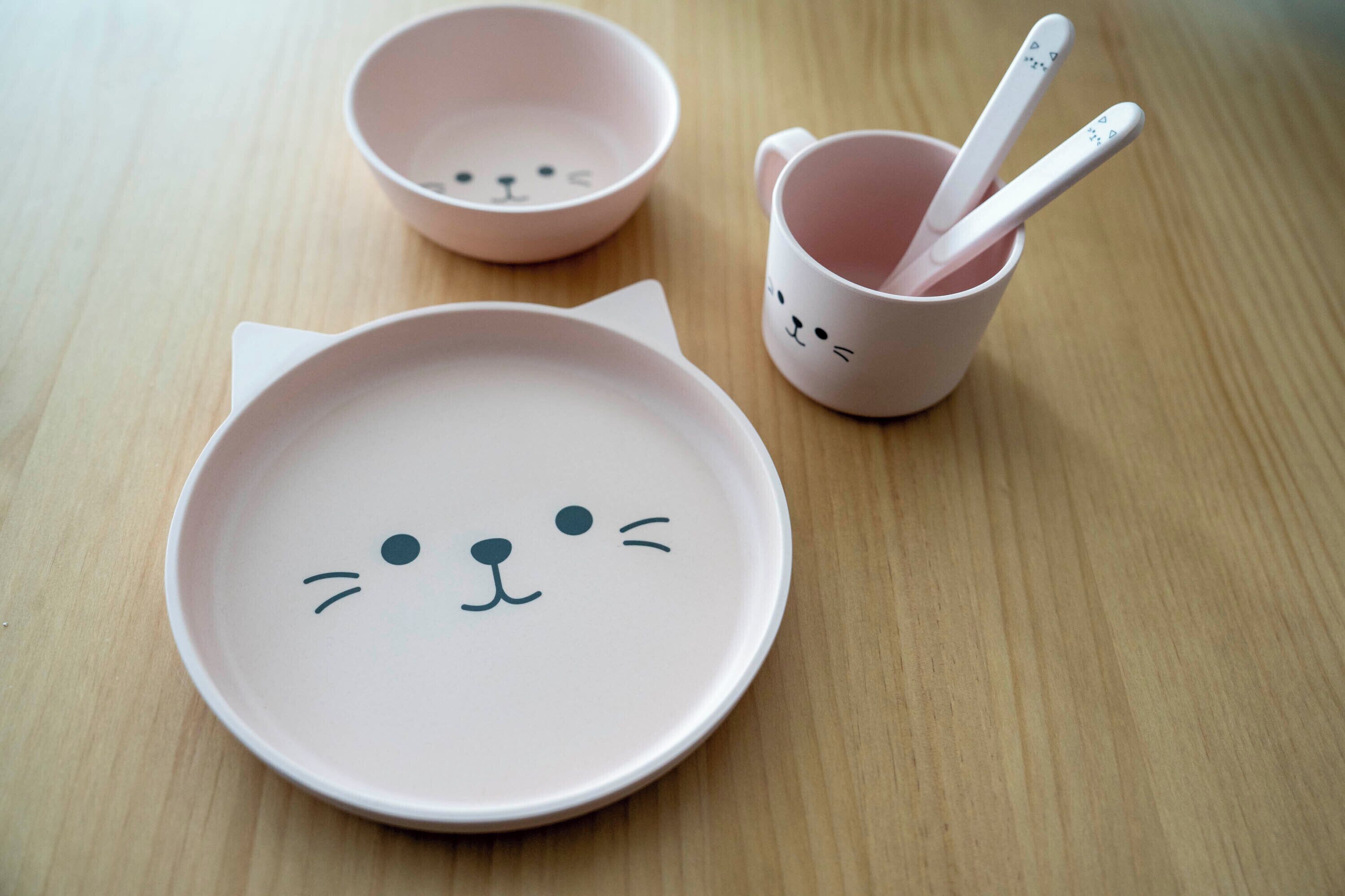 Ein Tisch mit einem rosa Teller, einer rosa Schüssel und einer rosa Tasse mit Katzenmotiv.