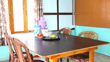 A dining table with chairs, a window with curtains, and a wall with a blue and brown color scheme.