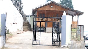 Un bâtiment en bois doté d’un porche couvert et d’une entrée fermée par un portail.