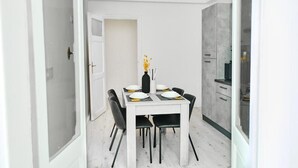 A modern dining area with a white table set for four, black chairs, and a vase with yellow flowers. - LABI HOME COLOSSEVM (Roma)
