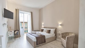 A bedroom with a bed, bedside lamps, a chair, a desk, and a TV. - LABI HOME COLOSSEVM (Roma)