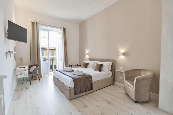 Une chambre à coucher avec un lit, des lampes de chevet, une chaise, un bureau et un téléviseur.