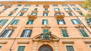 A multi-story building with a symmetrical facade, green shutters, and a central entrance with a decorative archway. - LABI HOME COLOSSEVM (Roma)