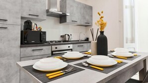 A modern kitchen with grey cabinets, a black microwave, and a dining table set with white plates and yellow utensils. - LABI HOME COLOSSEVM (Roma)