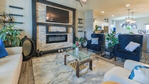 A modern living room with a fireplace, a glass coffee table, and comfortable seating. - Entire Home-Beautiful 4BR, 3.5BA Retreat in Ankeny, Iowa 2 King Beds, Fenced, AC (Ankeny)