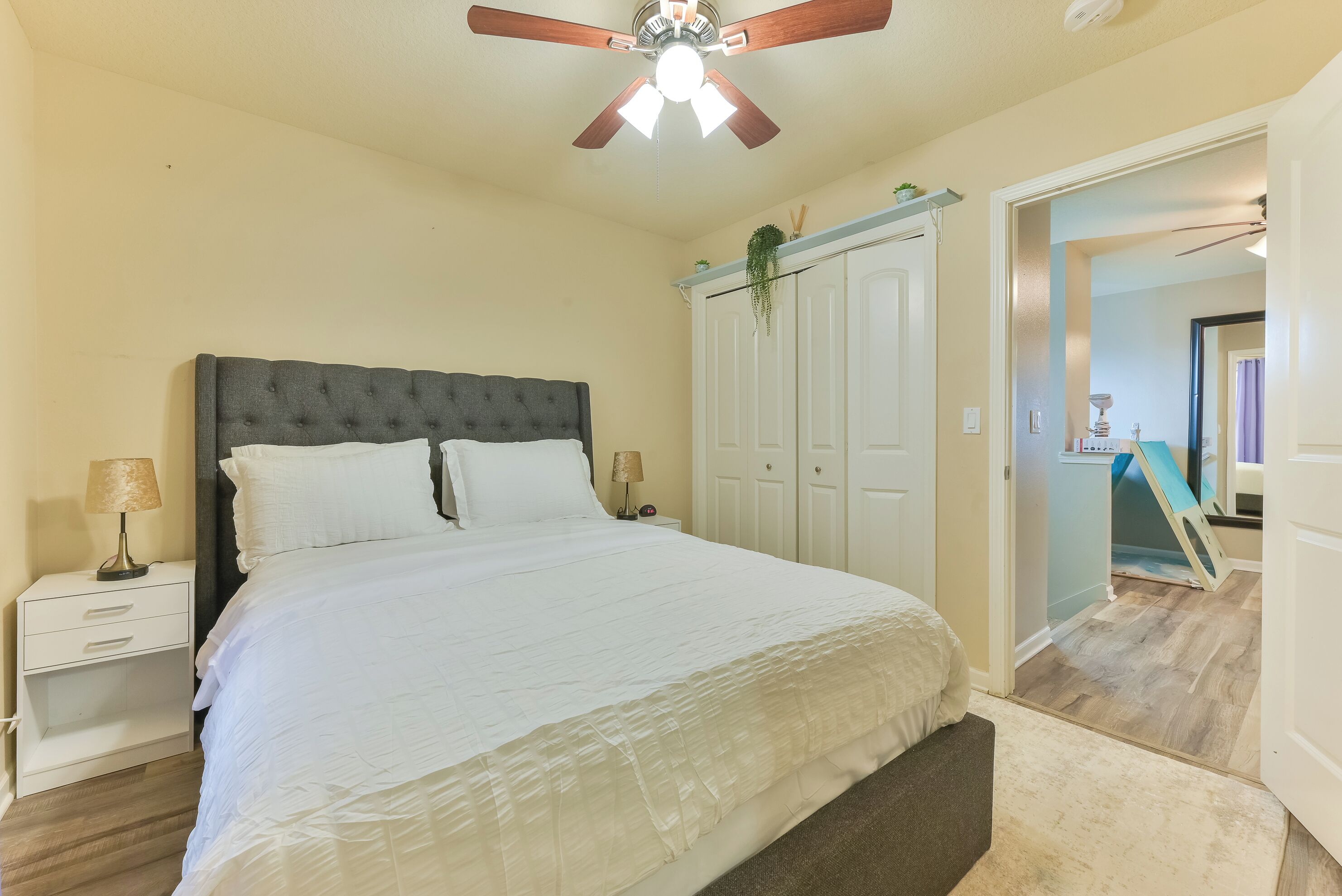 A bedroom with a bed, nightstands, a ceiling fan, and a wardrobe.