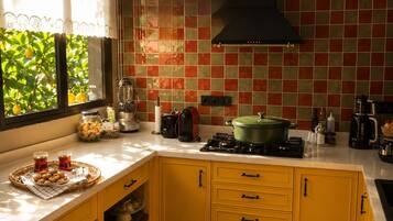 A kitchen with yellow cabinets, a gas stove, a green pot, and a window with a view of greenery.