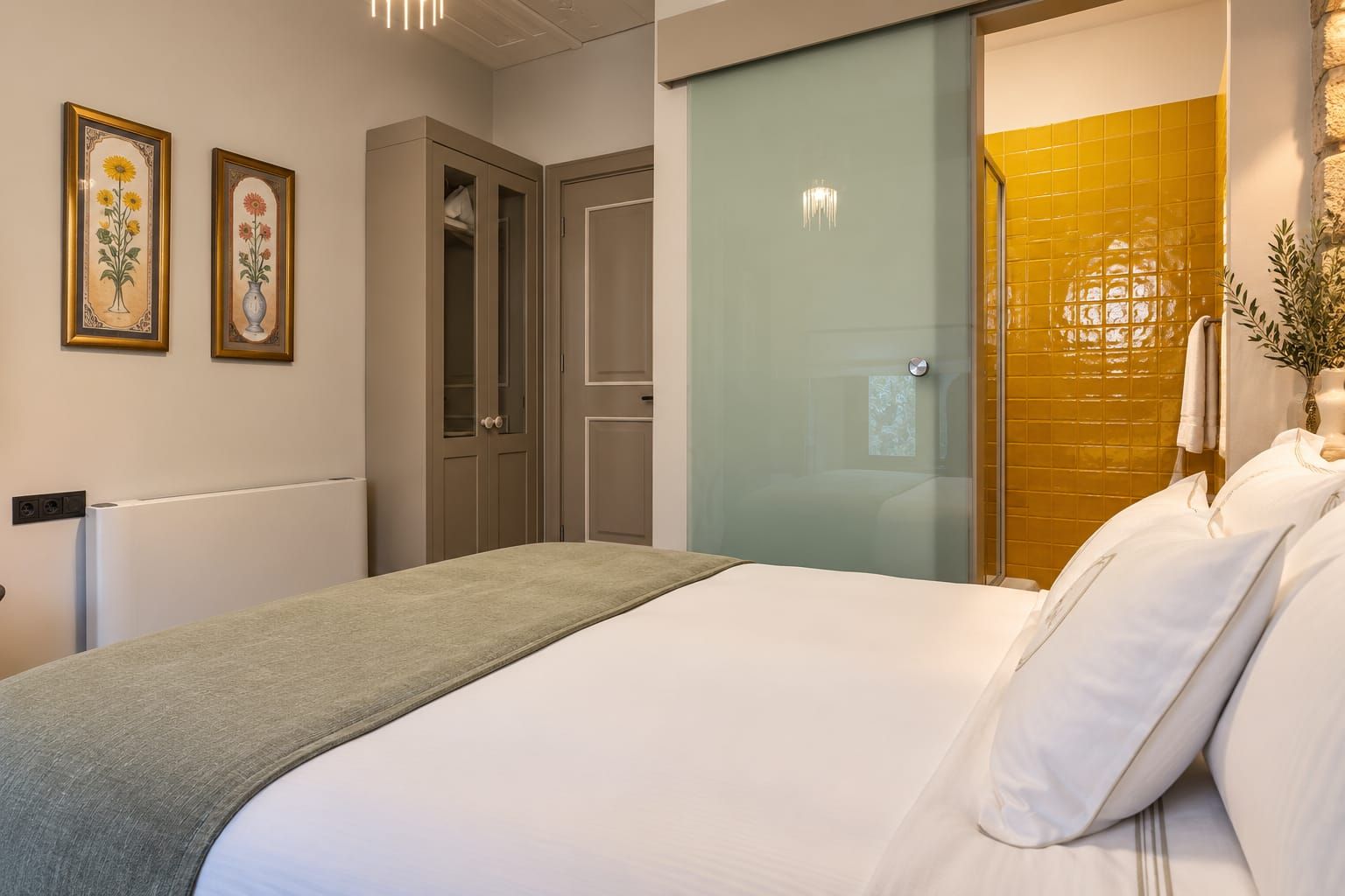 Un dormitorio con cama, armario, espejo y baño con ducha.