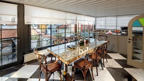 Une cuisine moderne avec une table à manger en verre, des chaises en bois et une vue sur la ville grâce à de grandes fenêtres.