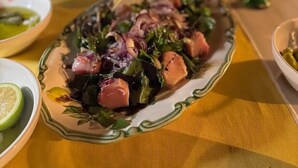 Un tavolo da pranzo con un piatto di cibo, un bicchiere di bevanda e una ciotola di insalata.