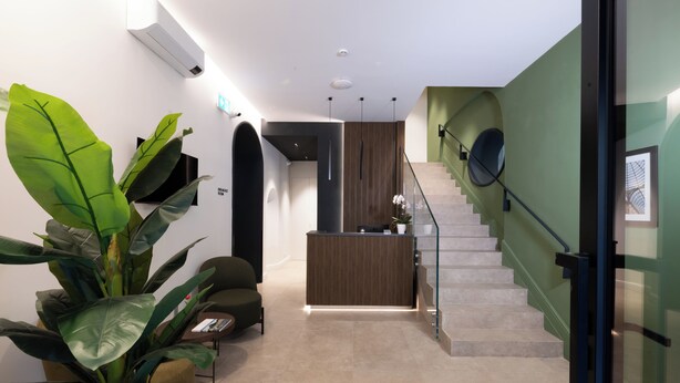 A modern reception area with a reception desk, a staircase, and a potted plant. - Casa D Hotel Napoli (Naples)