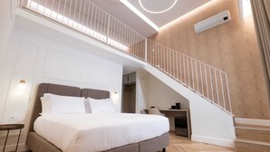 A modern bedroom with a large bed, a staircase, and a desk area. - Casa D Hotel Napoli (Naples)