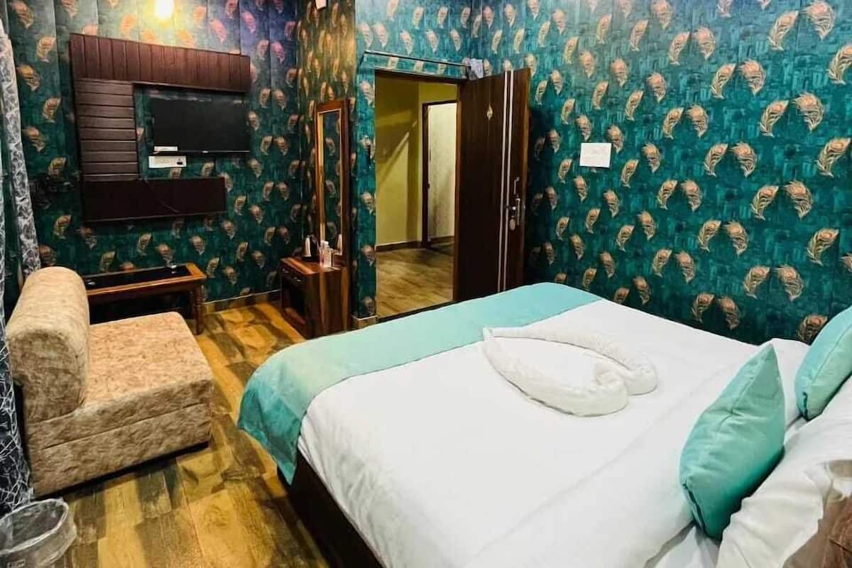 A bedroom with a bed, a chair, a TV, and a wardrobe.