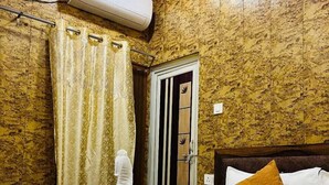 A hotel room with a bed, a shower, and a bathroom door. - Hotel Rajveer Inn (Varanasi)