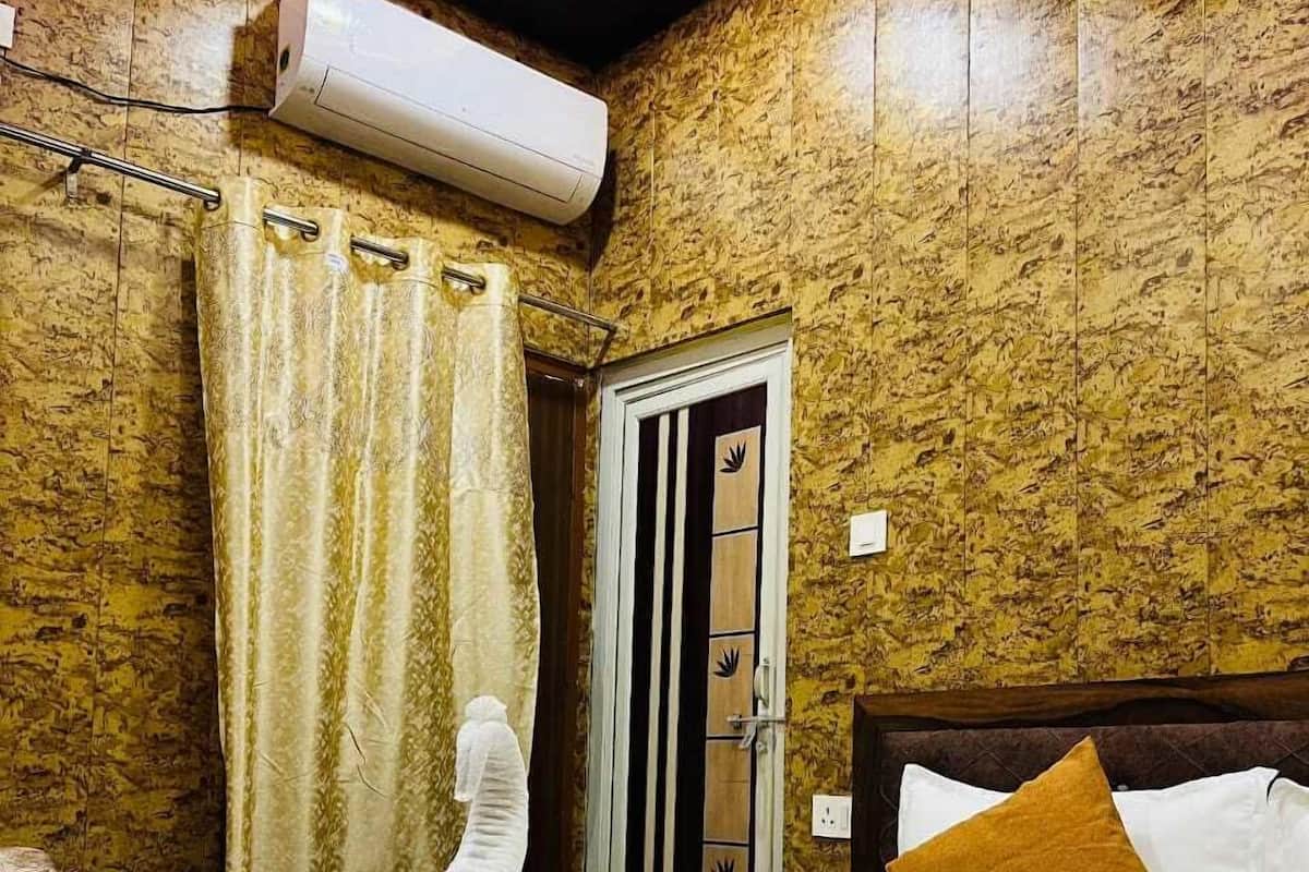 A hotel room with a bed, a shower, and a bathroom door.