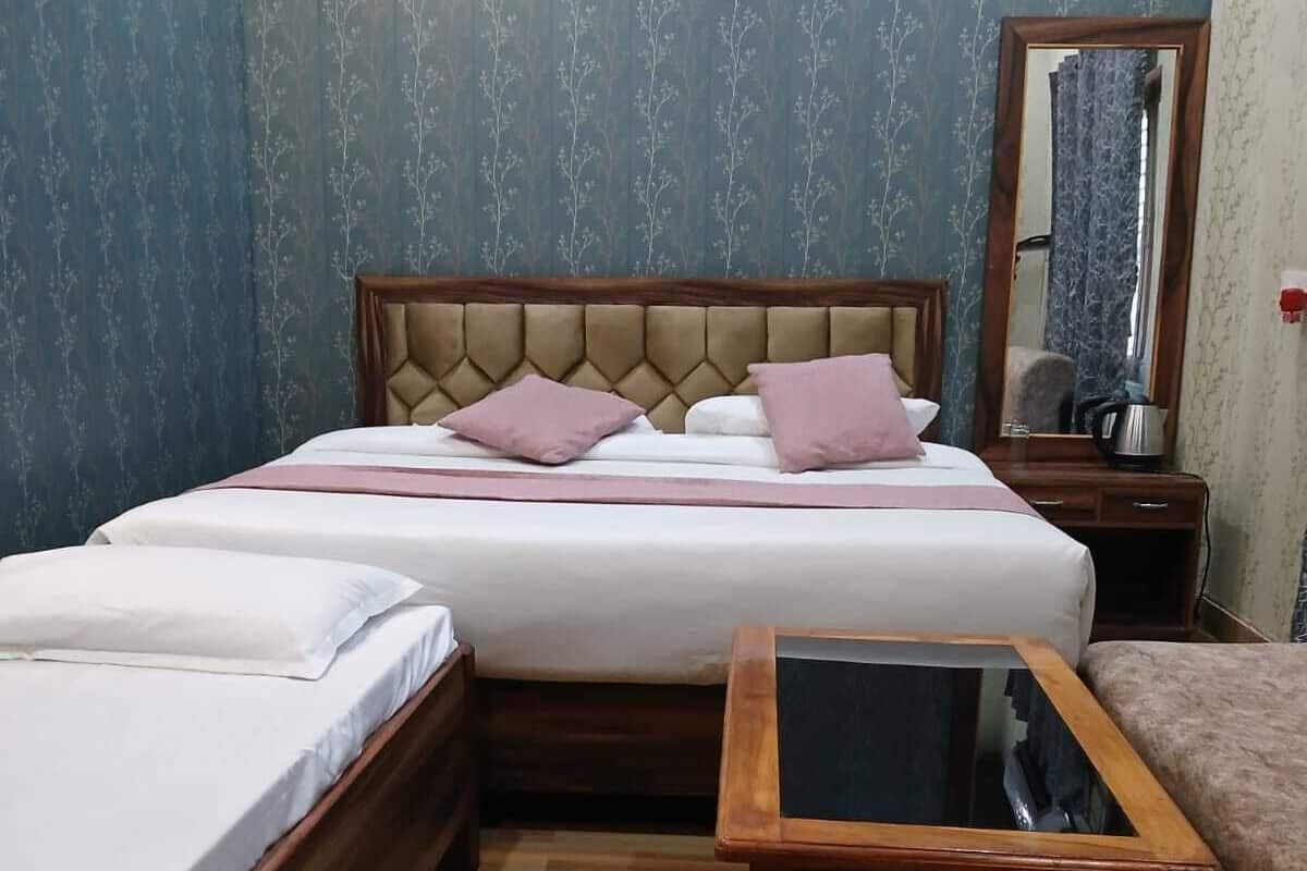 A hotel room with a bed, bedside table, and a mirror.