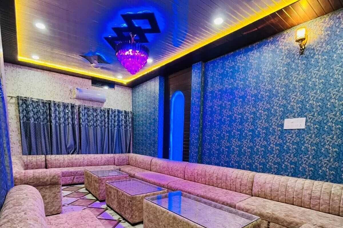 A room with a sofa area, tables, patterned walls, and a chandelier.