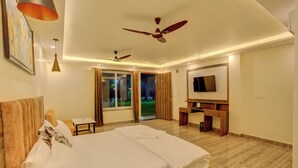 A hotel room with a large bed, a desk, a TV, and a balcony with curtains. - Bliss Resort (Rishikesh)