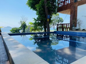 Una piscina con cubierta de madera y vista al mar.