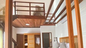 Een slaapkamer met een houten stapelbed, een grote spiegel en een kledingkast.