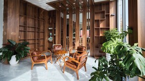 A modern interior with wooden shelving, leather chairs, and potted plants. - Lotus Hotel Da Lat (Xuan Truong - Da Lat)