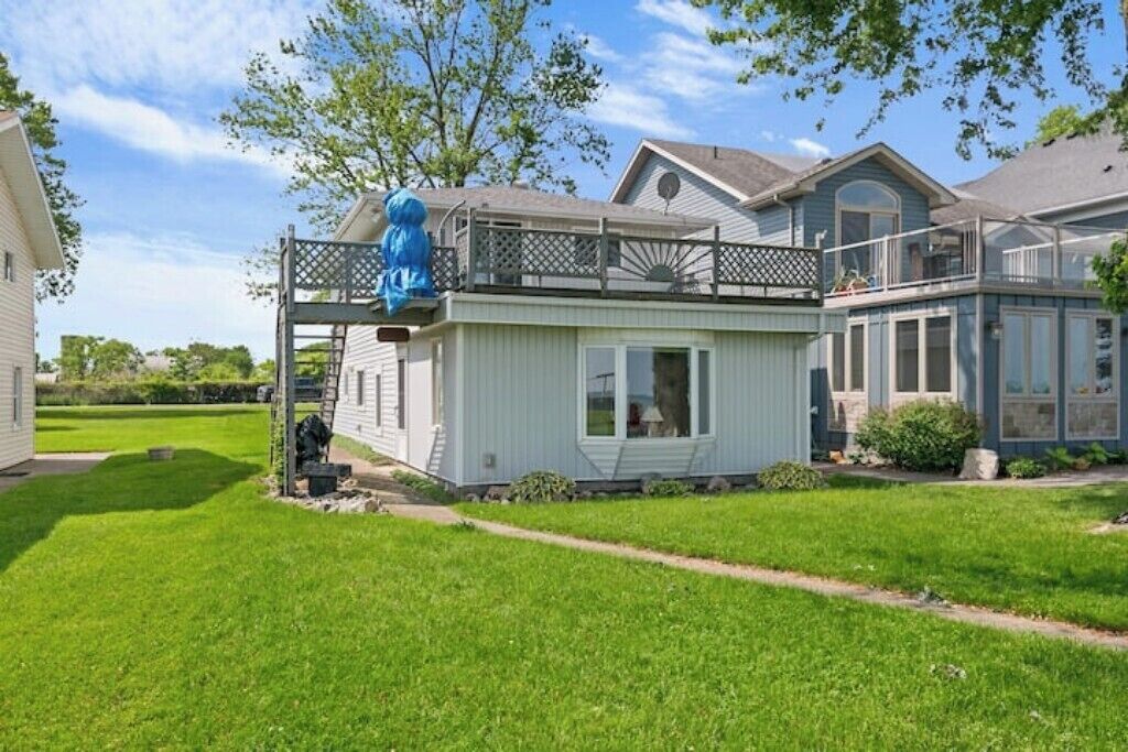 Een twee verdiepingen tellend huis met een balkon, een klein bijgebouw en een verzorgd gazon.