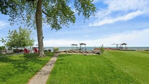 Un espace verdoyant bien entretenu, avec un chemin pavé, un petit pont et un kiosque au bord de l’eau.