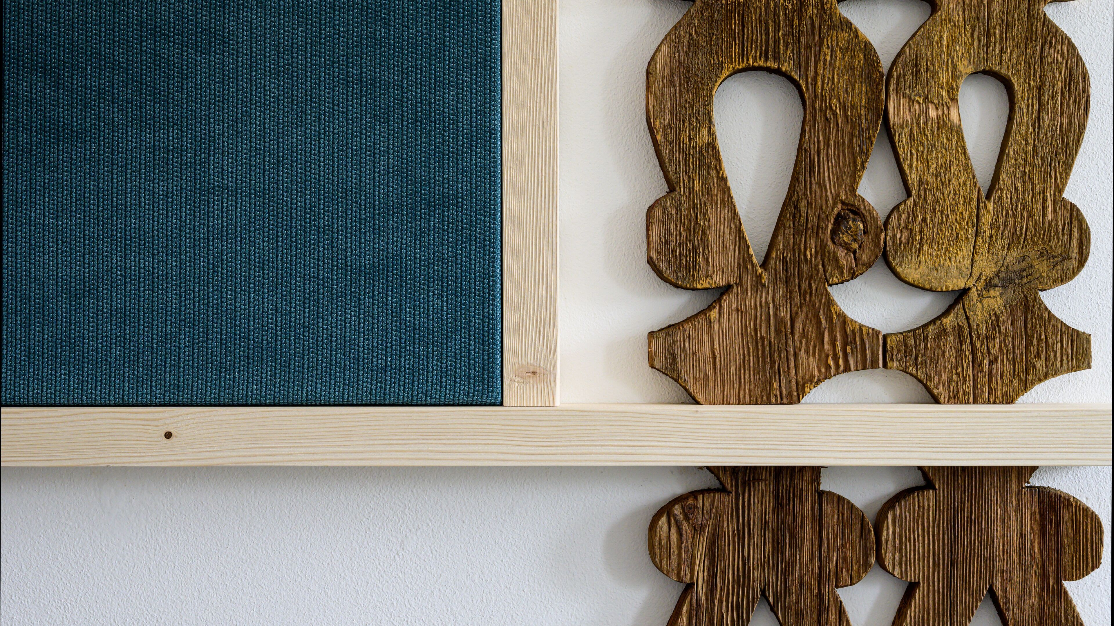 Ein Holzregal mit einem blauen Stoffpaneel und Holzformen.