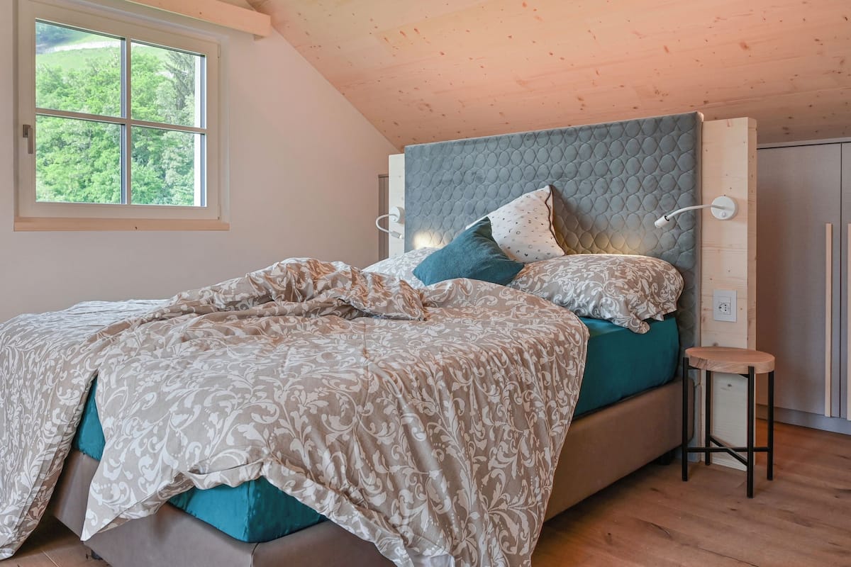 A bedroom with a bed, a nightstand, a window, and a wardrobe.