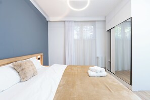A modern bedroom with a large bed, a fluffy pillow, and a set of towels.