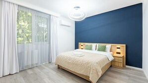 Moderni makuuhuone, jossa on suuri sänky, yöpöytä ja kattovalaisin.