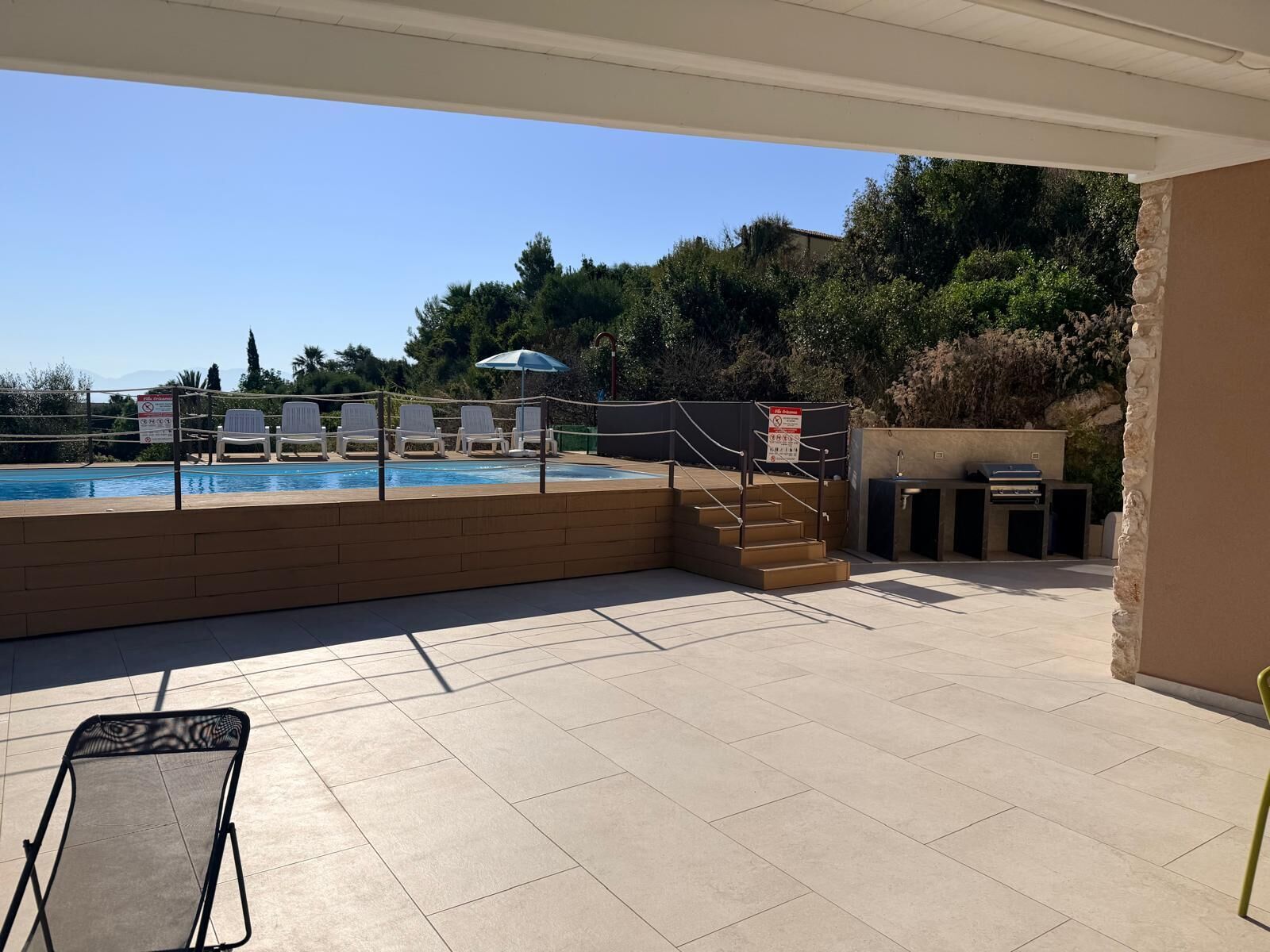 Un espace extérieur avec une piscine, des chaises longues et un barbecue.