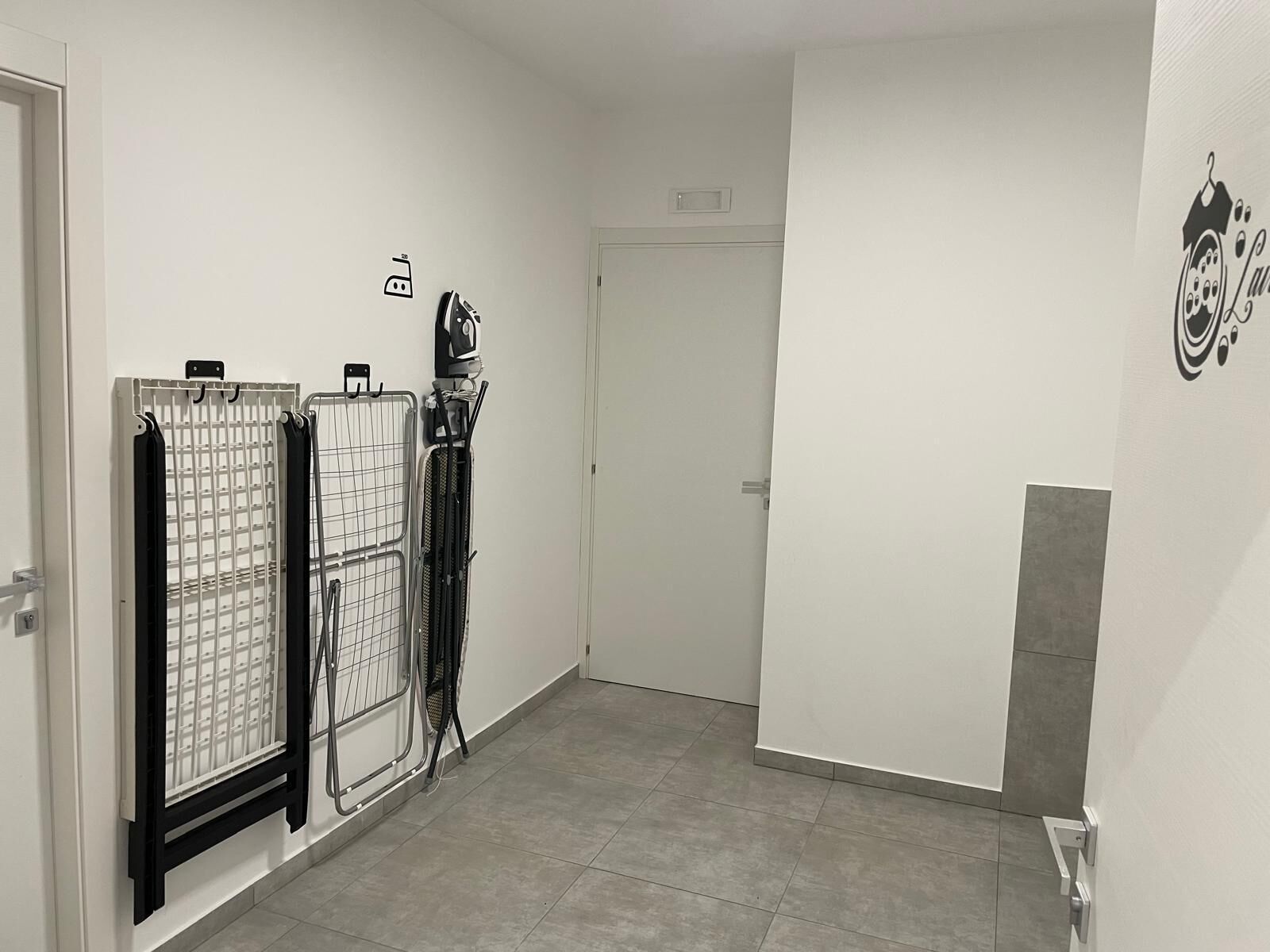 A hallway with a door at the end, a radiator, and a wall-mounted ironing board.