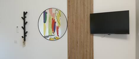A wall with a round mirror, a black TV, and a wooden panel.