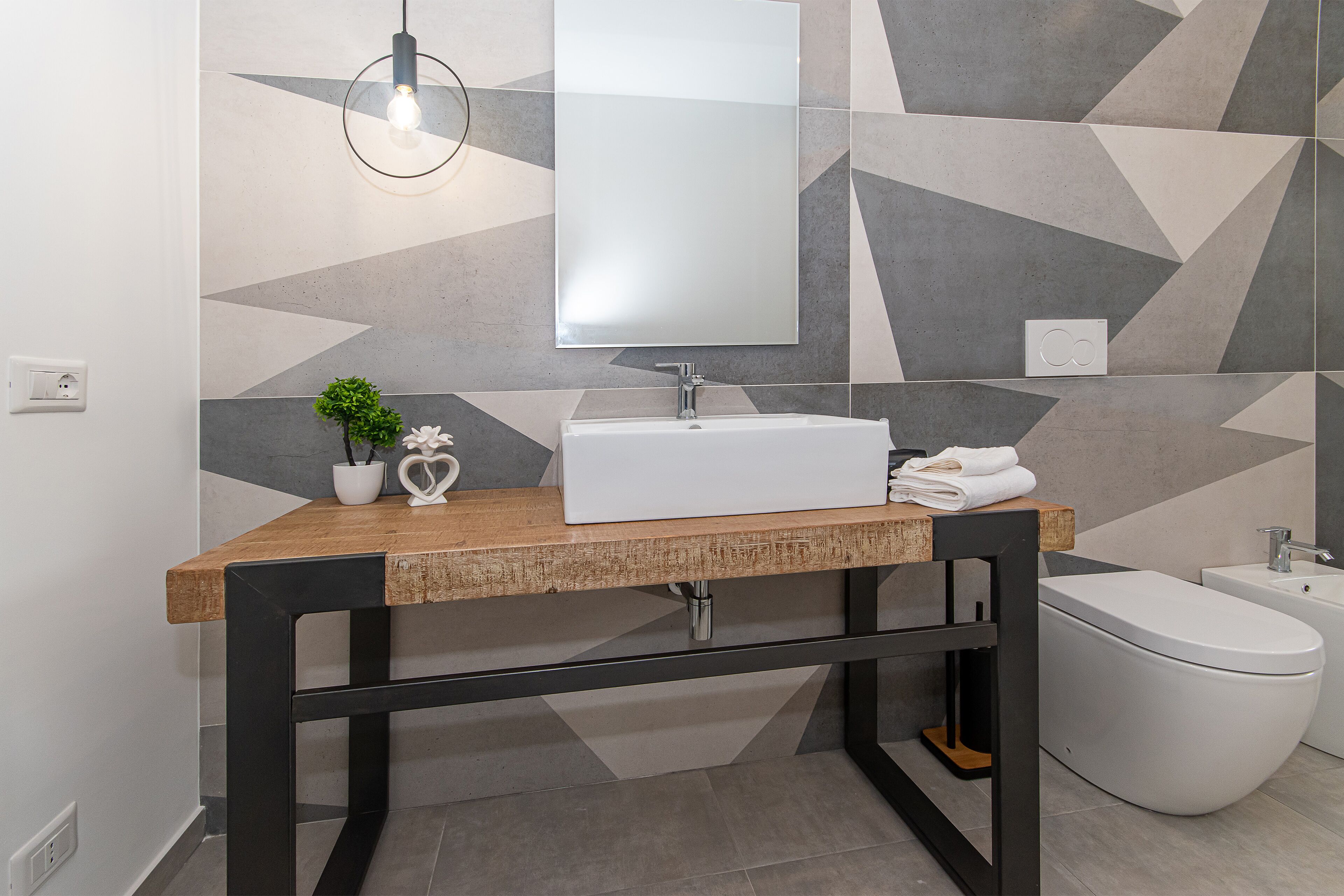 A modern bathroom with a wooden vanity, a white sink, and a toilet.