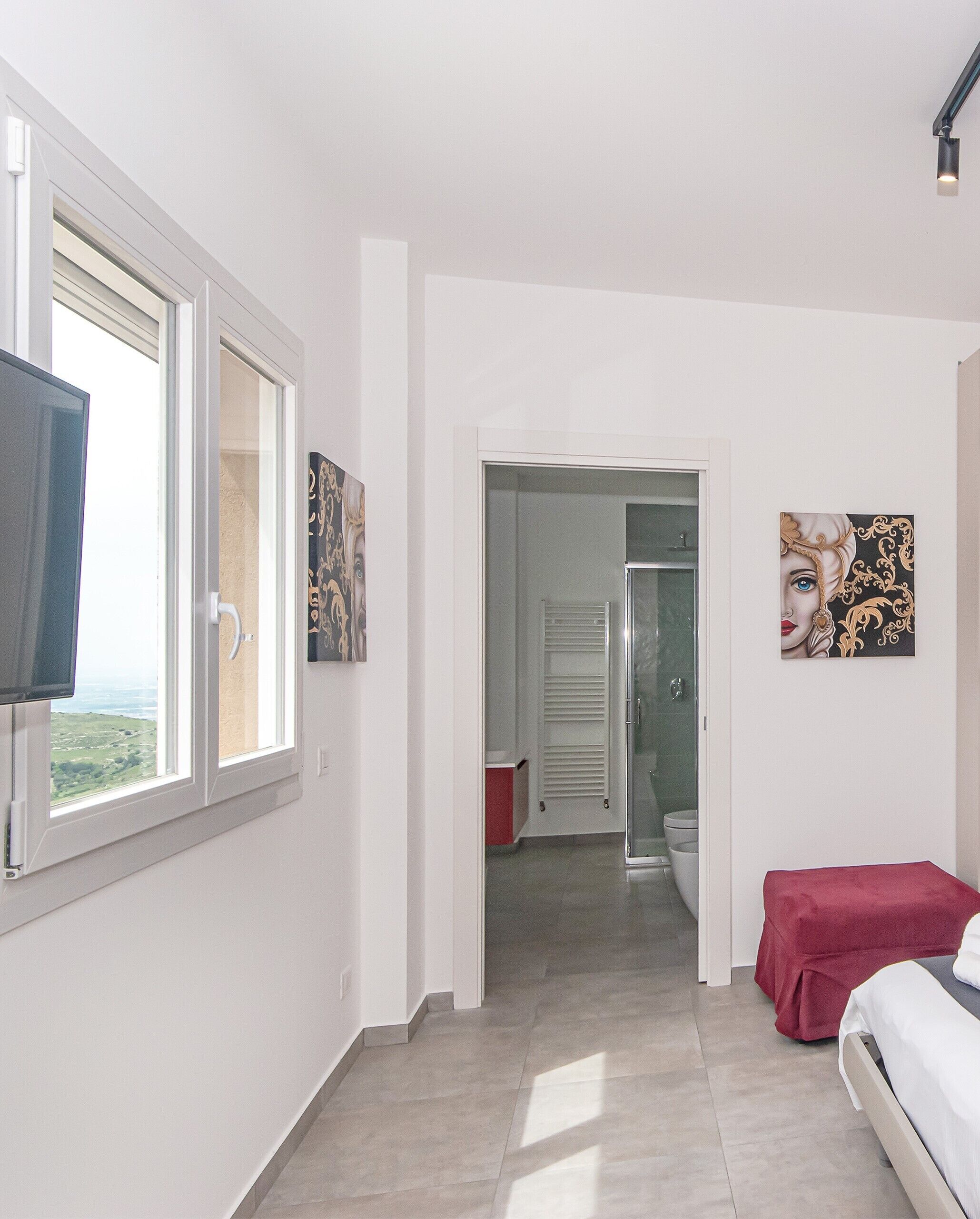 A bedroom with a bed, a TV, and a window with a view.