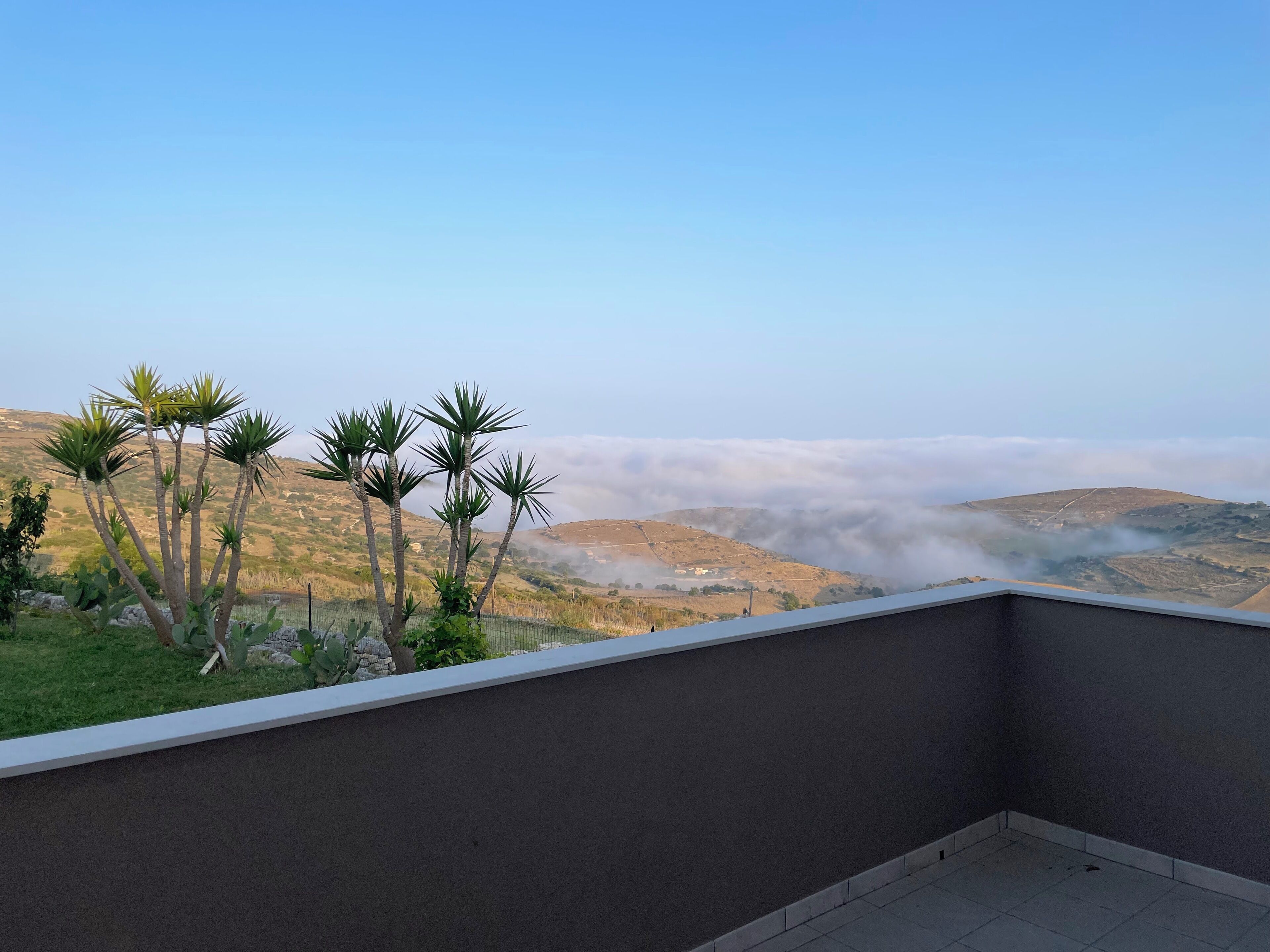 A balcony with a view of a mountainous landscape and a clear sky.
