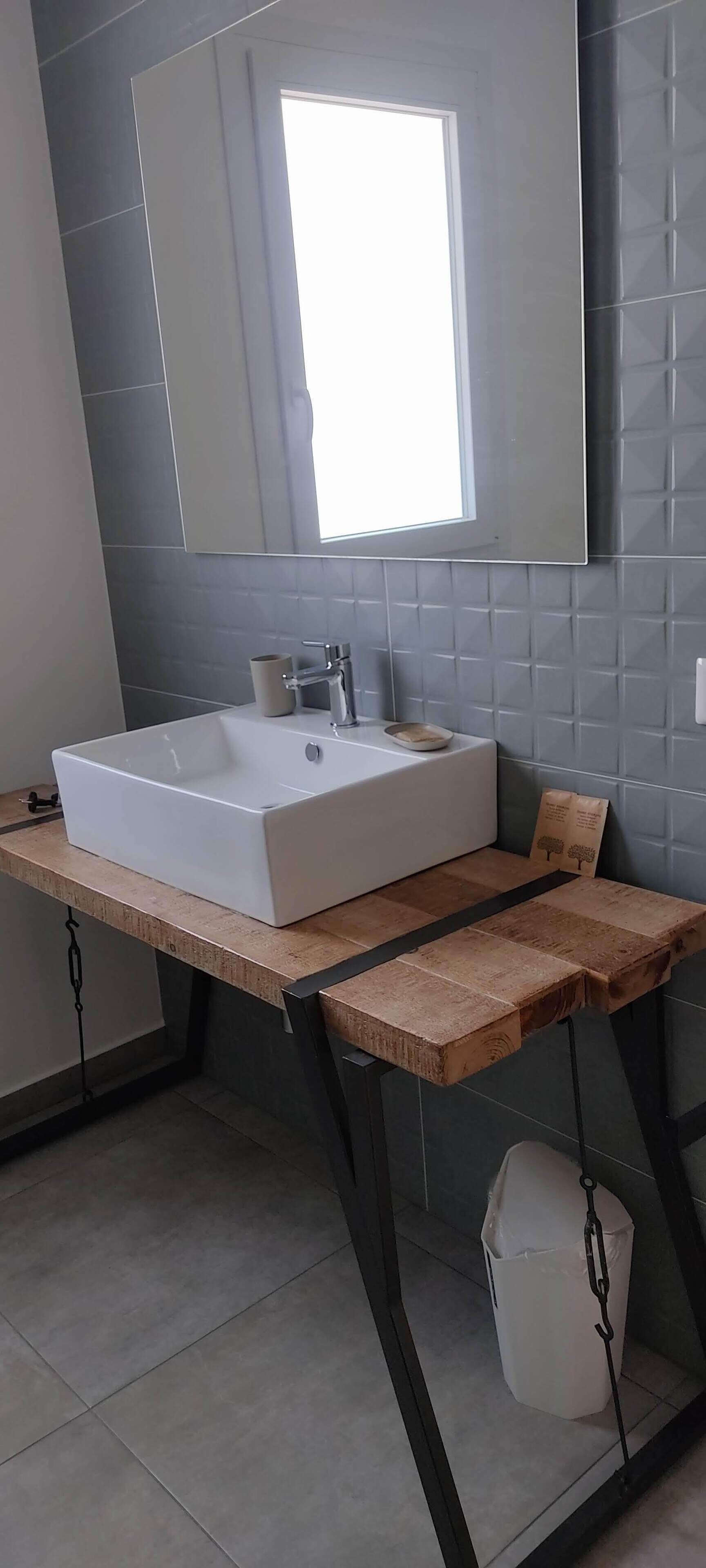 A bathroom with a large rectangular sink, a mirror above it, and a window providing natural light.
