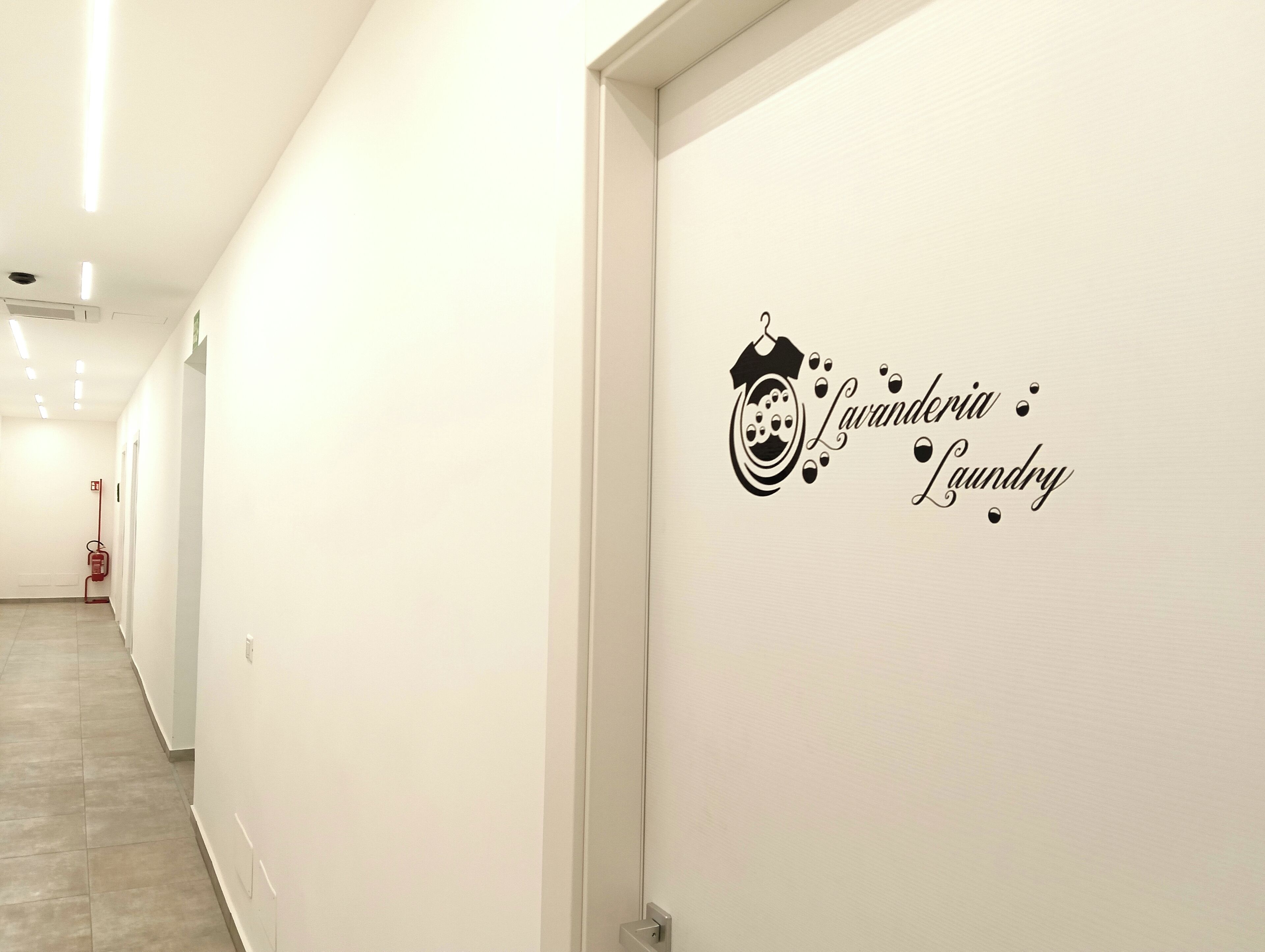 Un pasillo con un adhesivo en la pared que dice 'Lavandéria Laundry' y un extintor de incendios.