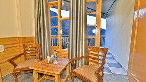 A wooden dining table with two chairs, a bottle of water, and a tissue box. - Hotel Sky Bhagsu (Dharamshala)