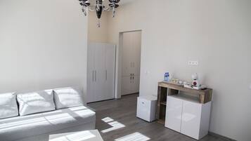 A modern, minimalistic living space with a grey sofa, a small white table, and a built-in wardrobe.