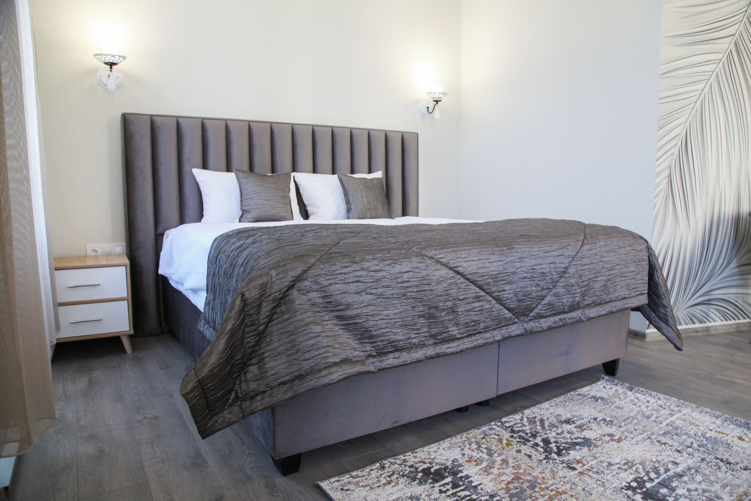 A bedroom with a large bed, a nightstand, and two wall-mounted lights.