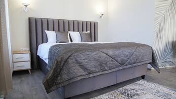 A bedroom with a large bed, a nightstand, and two wall-mounted lights.