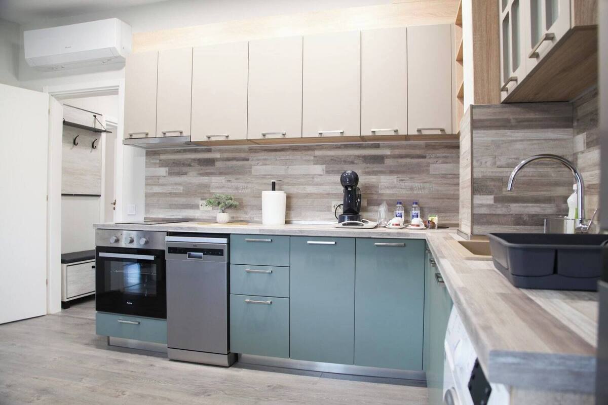 A modern kitchen with a built-in oven, dishwasher, and a large island with a sink.
