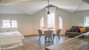 A spacious loft apartment with a dining area, a living room with a sofa, and a kitchen area. - Corner House (Lovech)